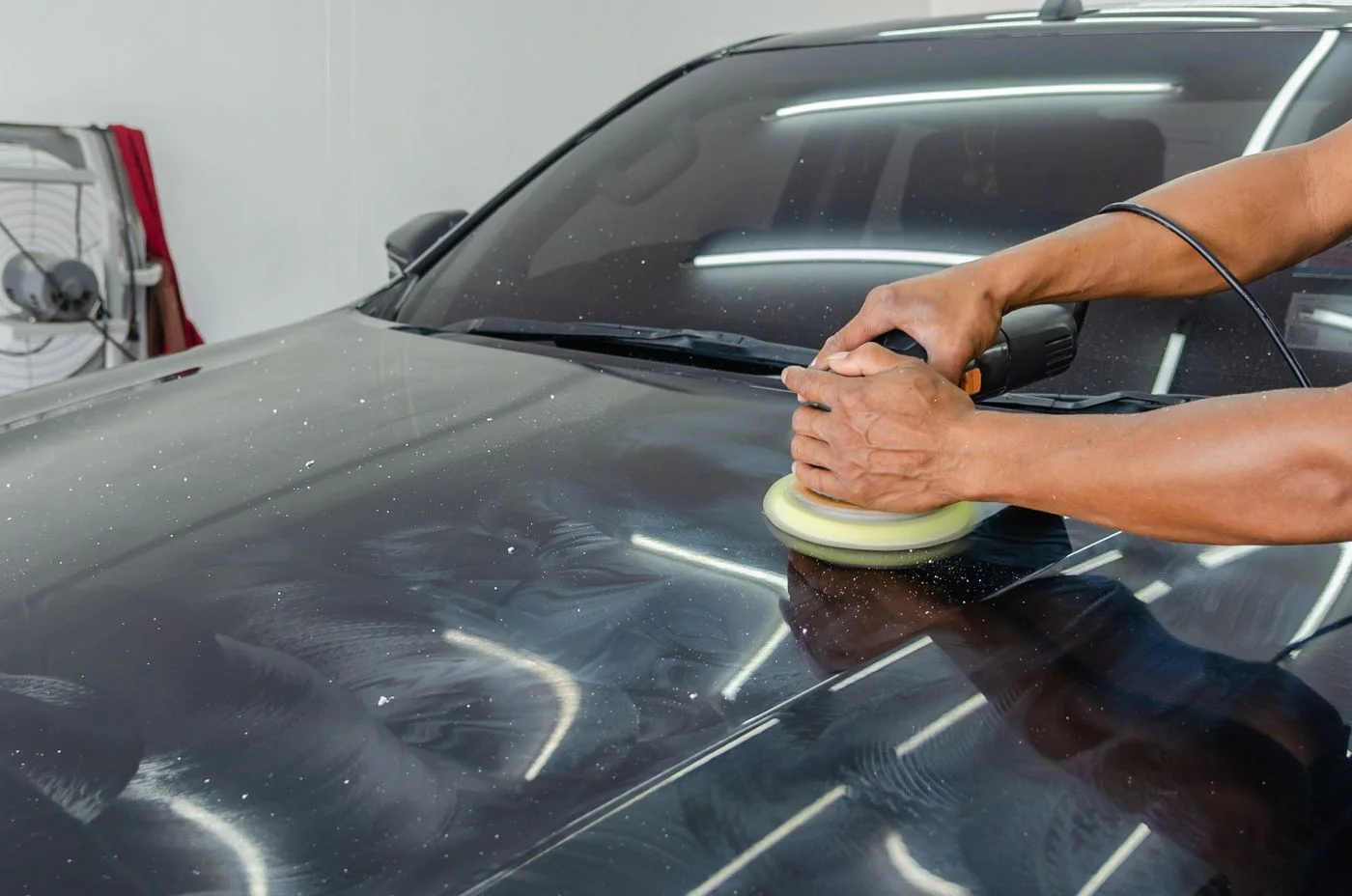 A detailer machine polishing a glossy vehicle in the Finishline demonstration photography