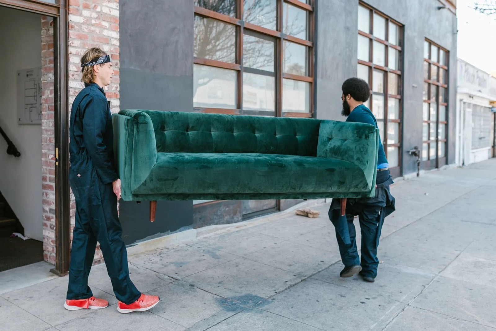 Two movers carrying a sofa along a residential street, from the Clearout demonstration photography